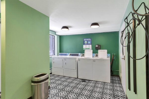 Bike storage and laundry room with green walls and geometric tiled floor.