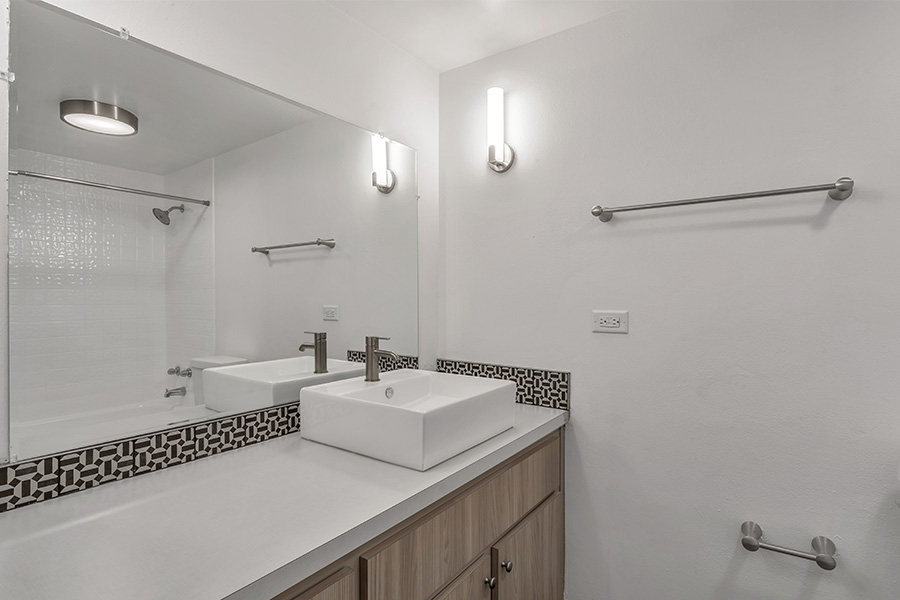 Bathroom with wood cabinets, light counters with basin sink, and large mirror.