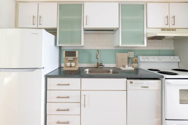 kitchen with blue back splash, white cabinets and stainless steel appliances