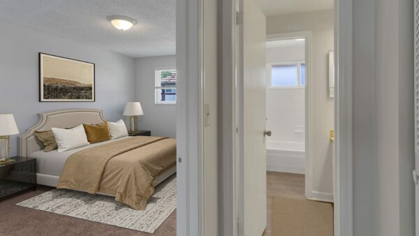 Bedroom with rug, plush bed and large window with blinds.