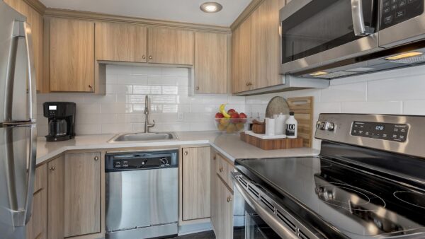 Kitchen with wood floor and cabinets, light counters, and stainless steel appliances.