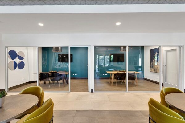 Meeting rooms with tables, modern chairs, wall mounted TVs, and glass walls.