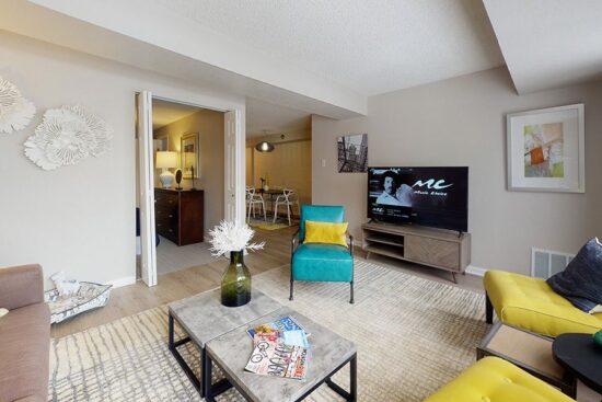 Living room with plush seating, modern furniture, large TV, and doors to bedroom and dining room.