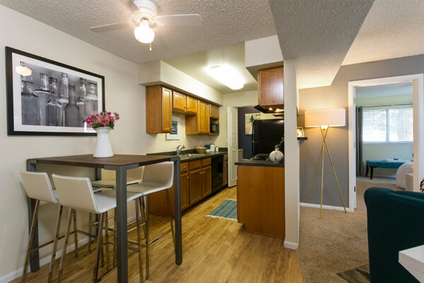 Living area with tall dining table, comfortable living room, and warm kitchen.
