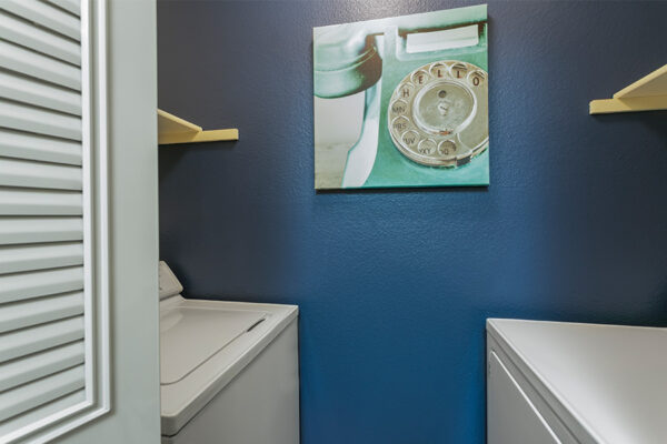 Laundry room with washer and dryer, blue accent wall, and photo of rotary telephone reading 