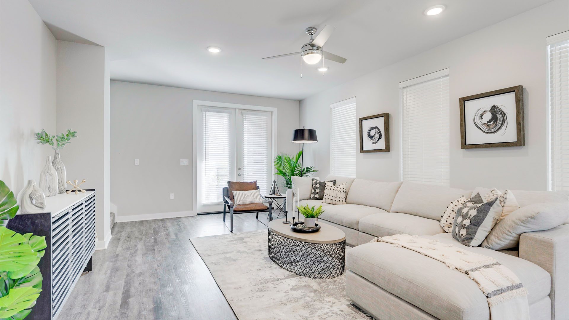 Living room with wood floor, rug, plush sectional, modern furniture, and door to balcony.