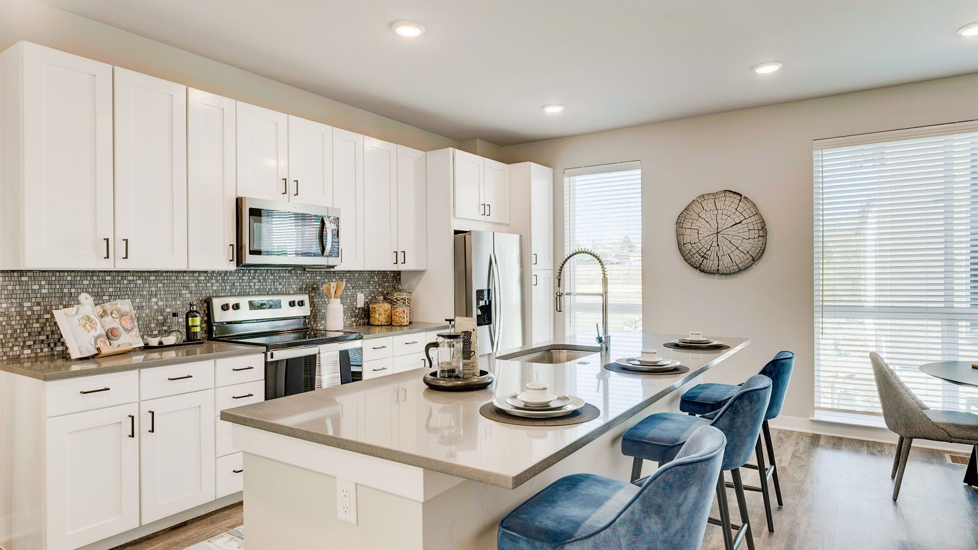 Kitchen with wood floor, white cabinets, tan counters, tiled backsplash, and breakfast bar.