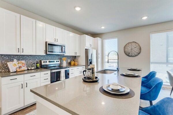Kitchen island with tan counters, modern place settings, and french press with bag of coffee.