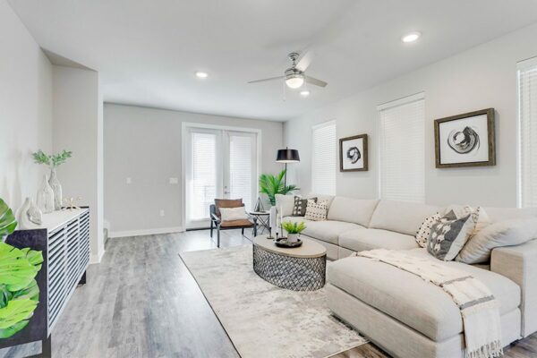 Living room with wood floor, plush sectional couch, modern furniture, and large windows.