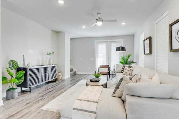 Living room with wood floor, plush sectional couch, modern furniture, and large windows.