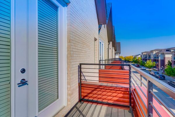 Balcony with metal railing and door to apartment overlooking street.