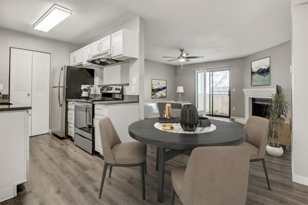 Living area with updated kitchen, dining room with modern furniture, and living room with fireplace and balcony door.