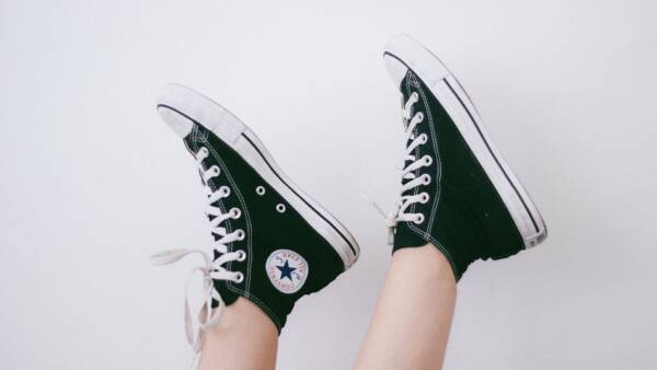 Detail of black Converse shoes in front of white wall.