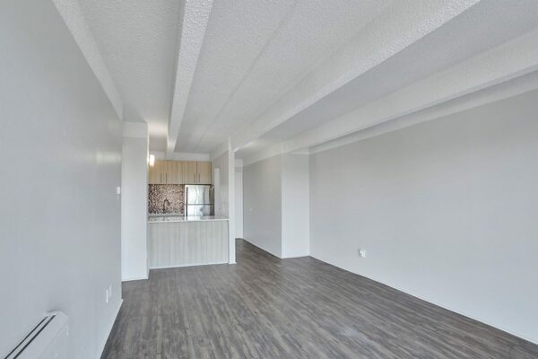 Living room with wood floor, grey walls, and opening to kitchen.