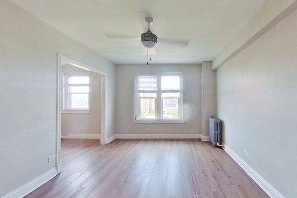 empty living room with window and fan at Novelist Apartments