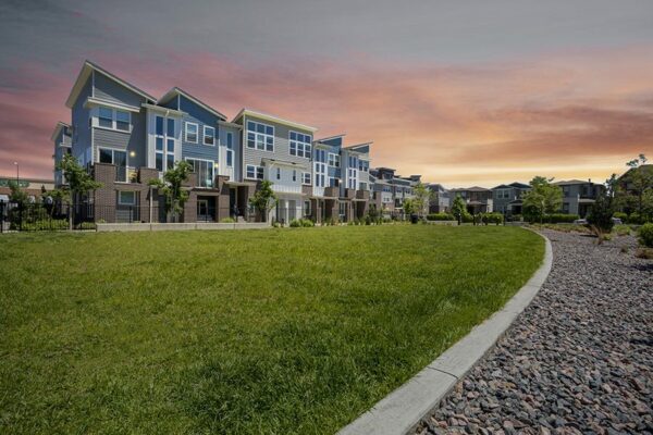 Platt Park townhomes at dusk with grassy lawn and rocky landscaping.