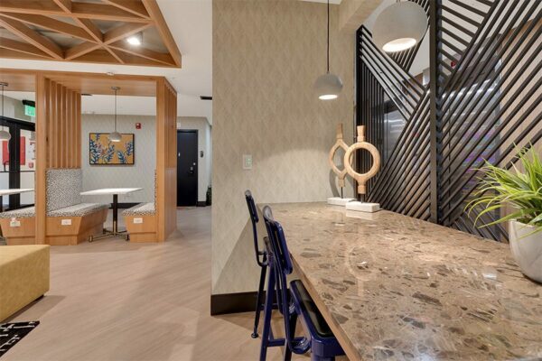 Lounge with wood floor, built in stone desk with chairs and decor, and decorative wall panels.