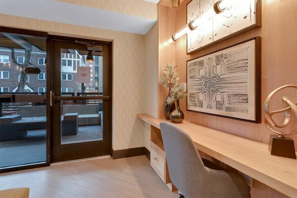 Lounge with built in desk with office chair and decor, wall art, and door to patio.