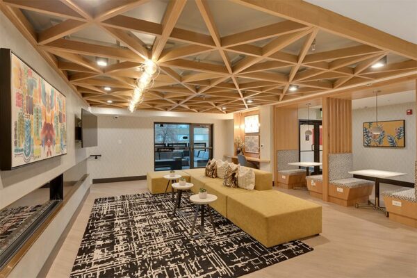 Lounge with wood floor, built in booths, large sectional couch, fireplace, and door to patio.