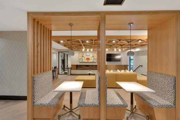 Modern built in booths with patterned seats, clean white tables, and pendant lights.