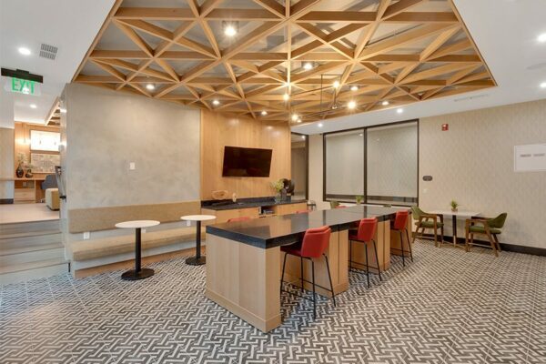 Lounge with geometric tile, large stone table, bench seats with tables, and wall mounted TV.
