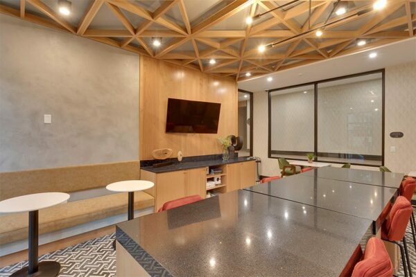 Lounge with geometric tile, large stone table, bench seats with tables, and wall mounted TV.