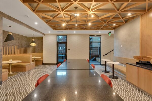 Lounge with large table, large round booths with tables, benches, and doors to patio.