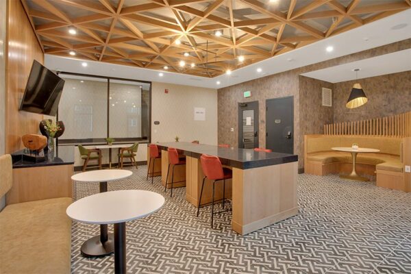 Lounge with large table, large round booths with tables, benches, and wall mounted TV.