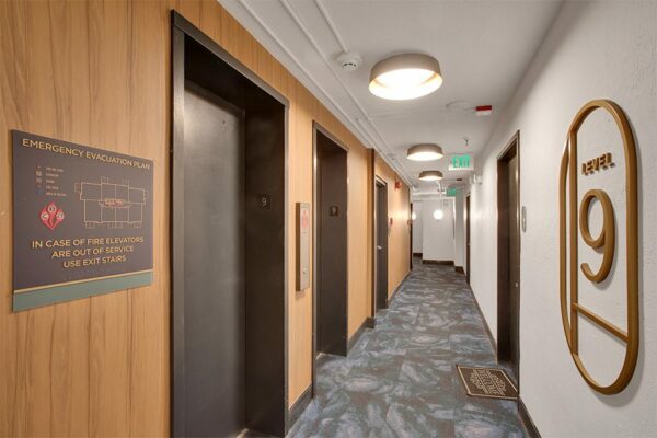 Hallway with pattern carpet, elevator doors, and large Level 9 decorative sign.