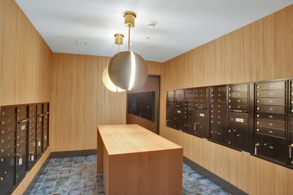 Mail room with pattern tile, wood wall panels, large light fixtures, and mailboxes.