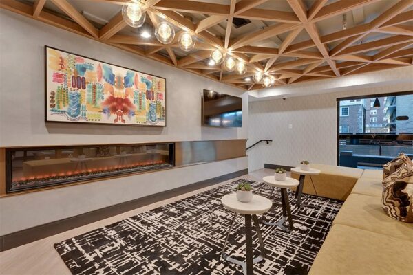 Lounge with wide modern fireplace, wall mounted TV, large sectional with coffee tables, and artwork.