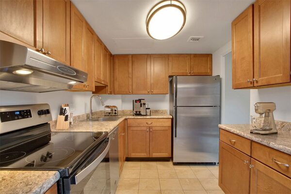 Kitchen with tile, wood cabinets, stone counter, and stainless steel appliances.