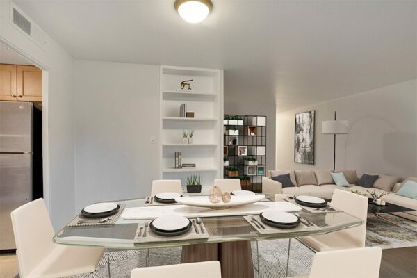 Living and dining room with wood floor, modern table, white leather sectional, and bookshelf with decor.