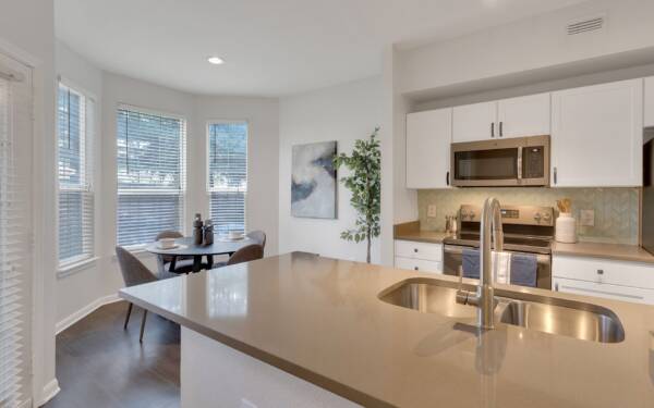 Dining room connected to living area and kitchen with wood floor and white walls.