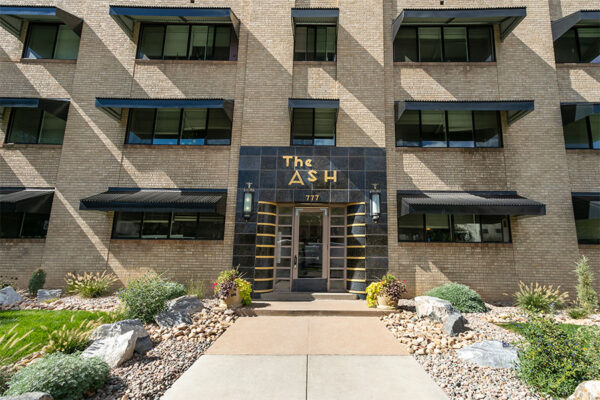 The Ash building with blonde brick construction and art deco tiled entry door.