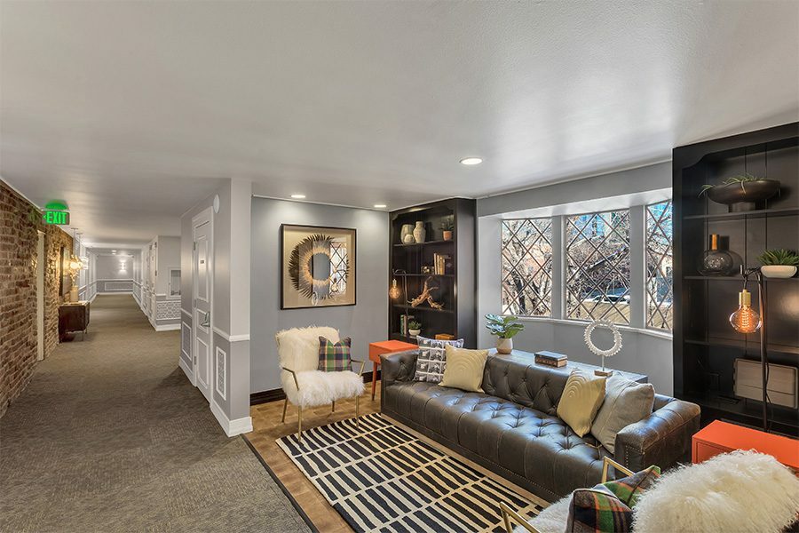 Lounge with plush furniture, built in shelves with eclectic decor, and large window.