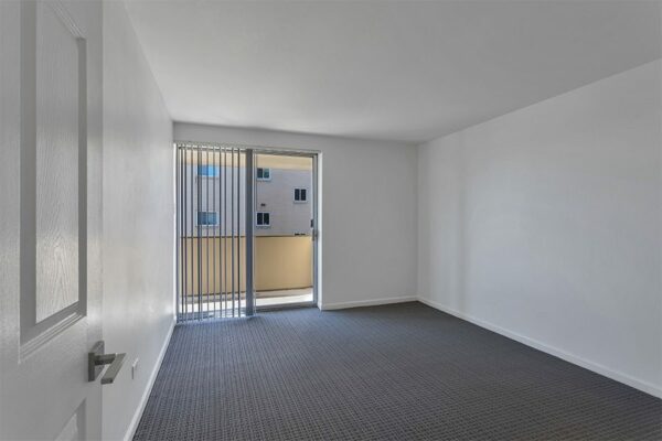 Bedroom with carpet, cool grey walls, and sliding door to balcony.