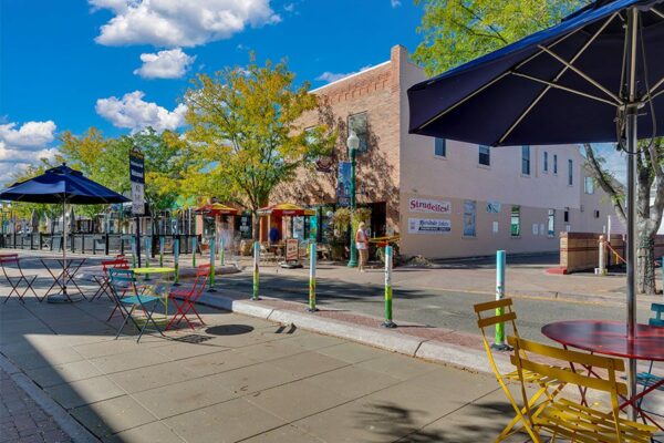 Street in Arvada lined with brightly painted chairs and tables with umbrellas.
