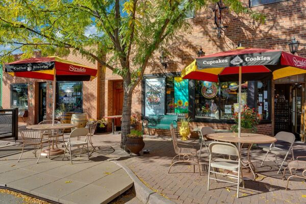 Tree lined street in Arvada with shops and outdoor dining.