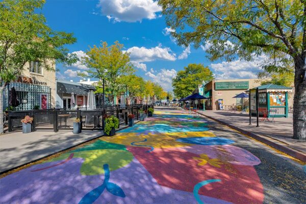 Olde Town Arvada street with sidewalk art and mature trees.