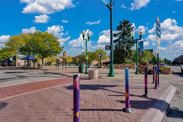 Olde Town Arvada sidewalk with art and tall trees.