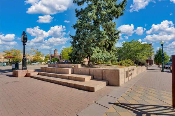 Olde Town Arvada square with stone sidewalks and tall trees.
