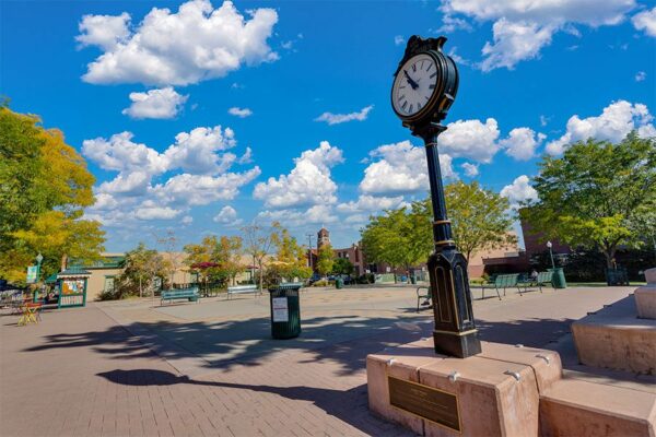 Olde Town Arvada square with tall trees and clock on post.
