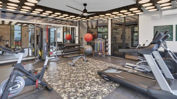 Fitness center with cardio machines, weight equipment, mirror walls, and decorative lights.