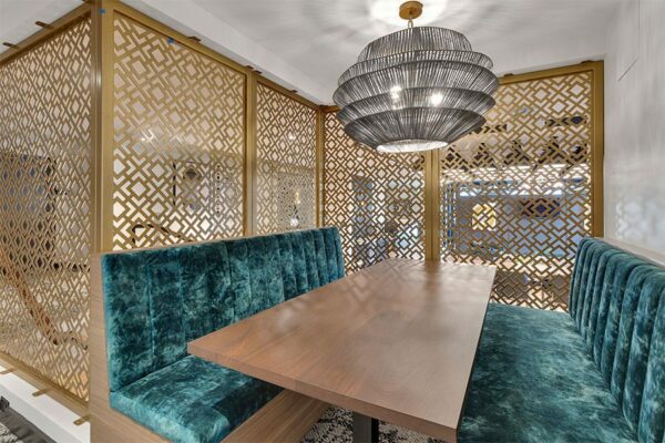 Detail of lounge booth with plush cushions, artistic light fixture, and decorative dividing panels.