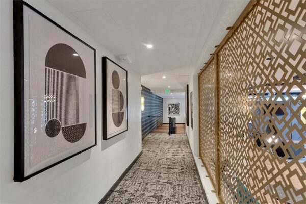 Hallway with carpet, decorative paneling, and geometric modern artwork.