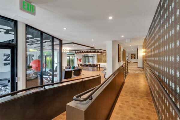 Lounge with wood floor, ADA ramp, modern furniture, and glass walled fitness center.