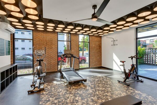 Fitness center with storage cubbies, cardio equipment, and large ceiling fan.