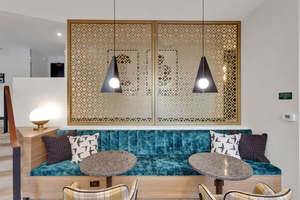Lounge with plush booth and tables, modern pendant lamps, and decorative wall panels.