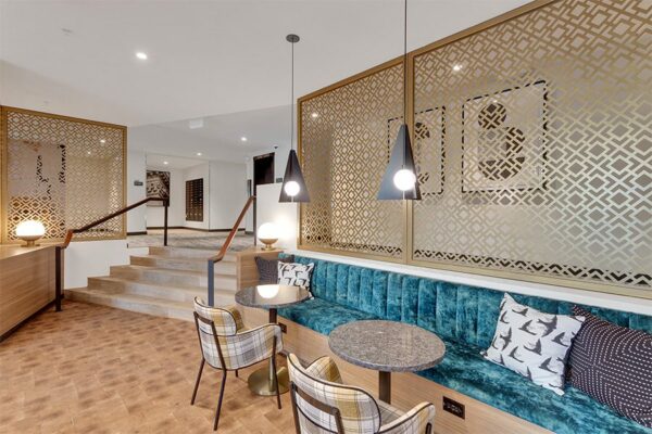 Lounge with plush booth and tables, modern pendant lamps, and decorative wall panels.